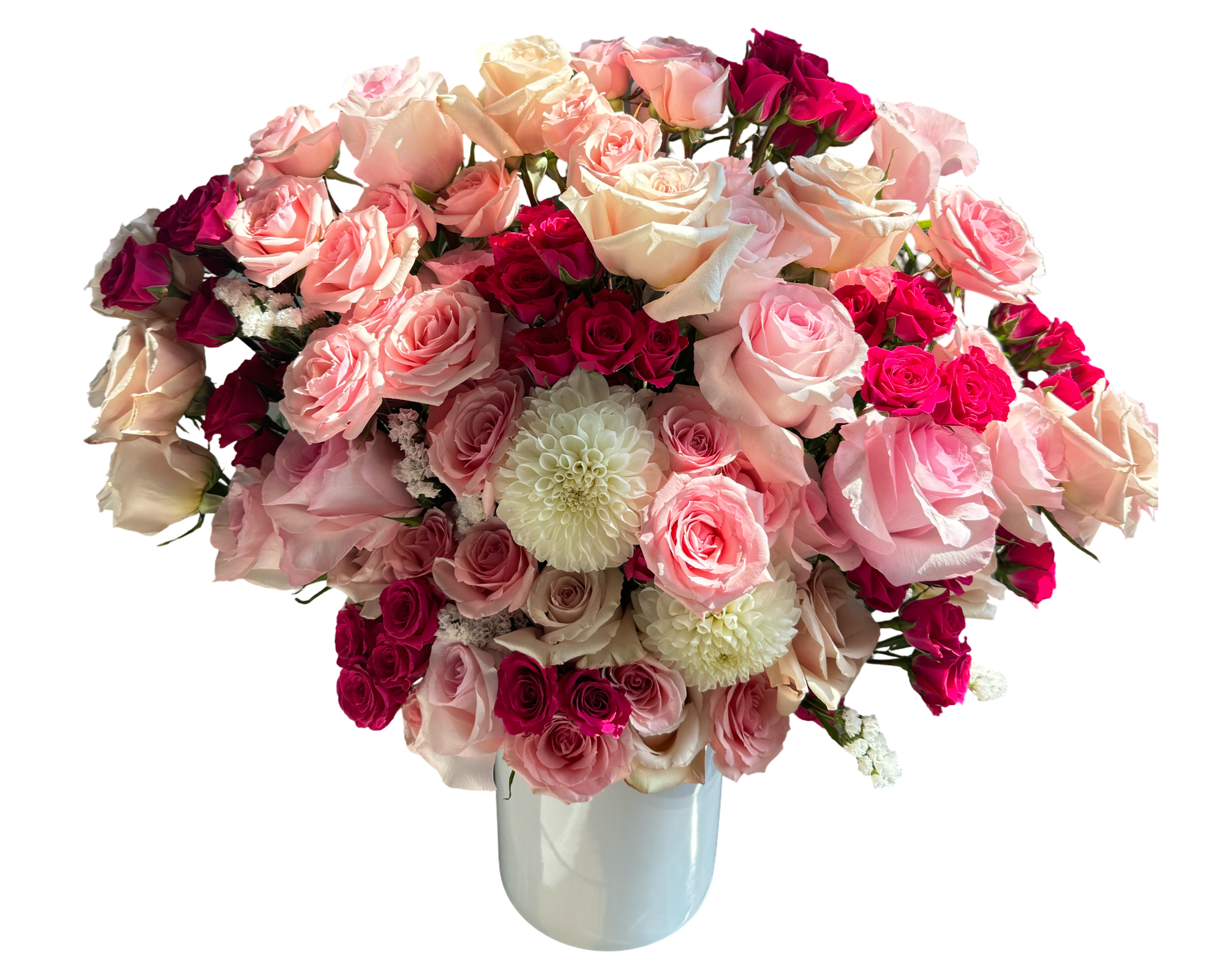 A lush and voluminous floral arrangement overflowing with shades of blush, pale peach, soft pink, and hot pink roses, accented by creamy white dahlias and set in a glossy white cylinder vase. The rich mix of full-sized roses and petite spray roses creates a classic, romantic silhouette that’s ideal for grand gestures, luxury gifts, and special milestones.