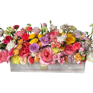 A lavish floral arrangement in a rectangular whitewashed wood box from L’amour Designs, filled with an abundant mix of multicolored roses, spray roses, carnations, lisianthus, stock, chrysanthemums, and alstroemeria. This explosion of color is accented with a gold “Happy Mother’s Day” topper, making it the ultimate floral gift to celebrate love, appreciation, and beauty.