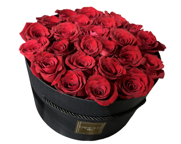 A luxurious and classic floral presentation featuring deep red roses meticulously arranged in a sleek round black hatbox from L’amour Designs. The tight dome of velvety roses is rich in color and romance, making it a bold and unforgettable gift—perfect for grand gestures of love and admiration.