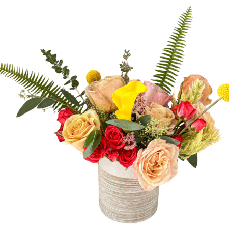 Amber Flame floral arrangement with golden roses, yellow calla lilies, and greenery in a ribbed tan ceramic vase.